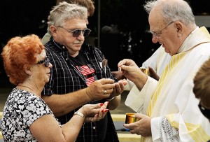 Bishop Robert N. Lynch distributes the Eucharist to the faithful during the Memorial Day Mass at Calvary Catholic Cemetery on May 28.