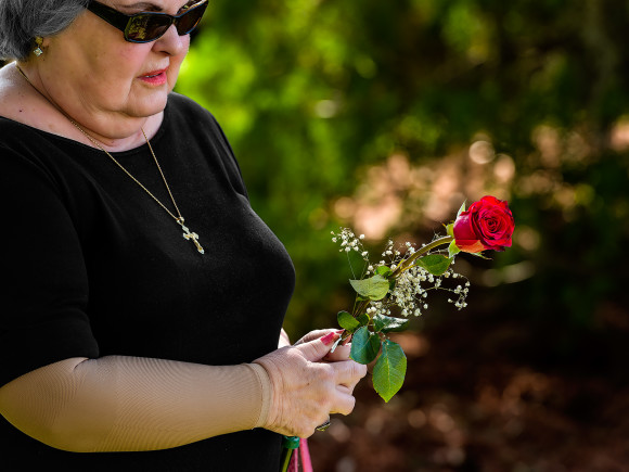 While joining in the Prayer of the Faithful, Rose Stalikas holds a lone red rose she brought to place on the grave of her sister, Angela Stalikes, who passed away on July 27, 2015.