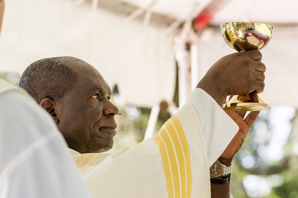 Principal Celebrant, Father Charles Leke, raises the chalice of Precious Blood after consecration at Mass on Memorial Day.