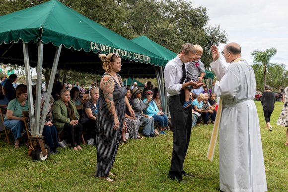 A young family receives Holy Communion during Mass at Calvary Catholic Cemetery, Clearwater, Fla.
