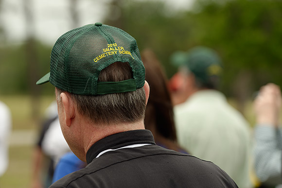 Msgr. Baver sports one of the trademark green, John Deere caps as he listens to a presentation by representatives of the John Deere company.
