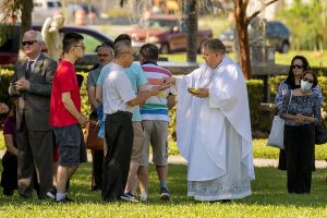 Msgr. Michael Muhr distributes Communion during the Mass on All Souls' Day at Calvary Catholic Cemetery.