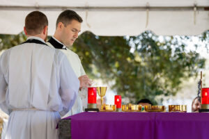 Fr. Ralph D'Elia, III and Fr. Victor Amorose (at left) prepare the altar for the Liturgy of the Eucharist during Mass on All Souls' Day at Calvary Catholic Cemetery.