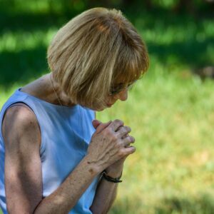 Kathy DiLuzio kneels as she prays after receiving the Eucharist at Mass on Memorial Day at Calvary Catholic Cemetery, Clearwater, Fla.