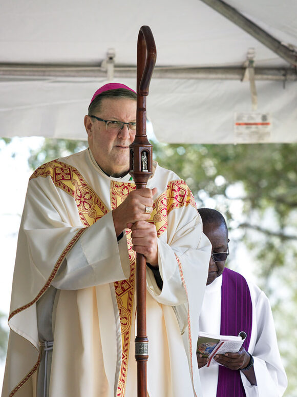 With his Crozier in hand, Bishop Parkes listens to the Gospel Reading in which Jesus spoke to the crowds in part, “For this is the will of my Father, that everyone who sees the Son and believes in him may have eternal life, and I shall raise him on the last day.”